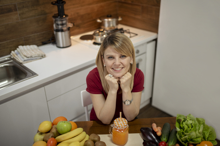 Young woman drinking smoothie in the kitchen. Close up portrait of young woman in the kitchen. Healthy Food - Vegetable Salad. Diet. Dieting Concept. Healthy Lifestyle. Cooking At Home. Prepare Foodの写真素材