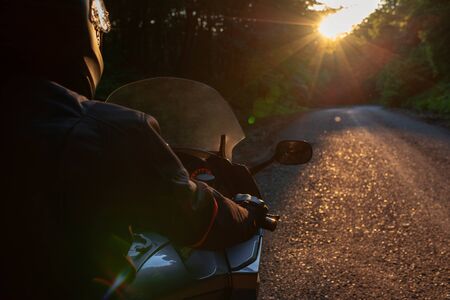 Biker with his motorcycle on street, preparing for the ride. Motorcycle guy with motorcycle on the road.Driver riding motorcycle on the road through forest.The view over the handlebars of motorcycle.の写真素材