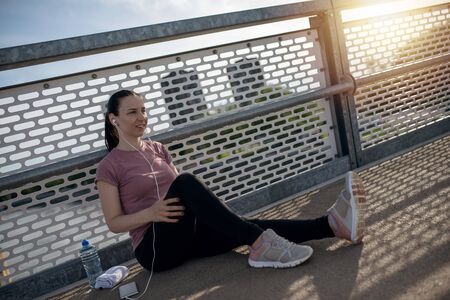 Sunset exercise with beautiful, sport woman. Woman fitness jogging, workout wellness concept. Female runner listening to music while joggingの写真素材