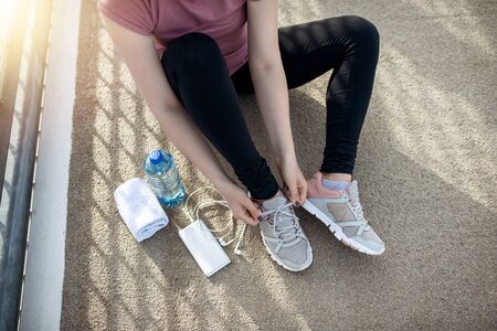 Sunset exercise with beautiful, sport woman. Woman fitness jogging, workout wellness concept. Female runner listening to music while joggingの写真素材
