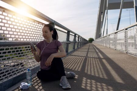 Sunset exercise with beautiful, sport woman. Woman fitness jogging, workout wellness concept. Female runner listening to music while joggingの写真素材