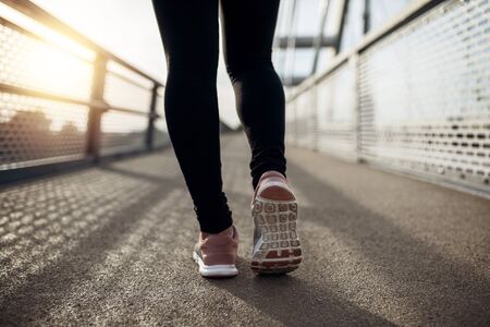 Sunset exercise with beautiful, sport woman. Woman fitness jogging, workout wellness concept. Female runner listening to music while joggingの写真素材