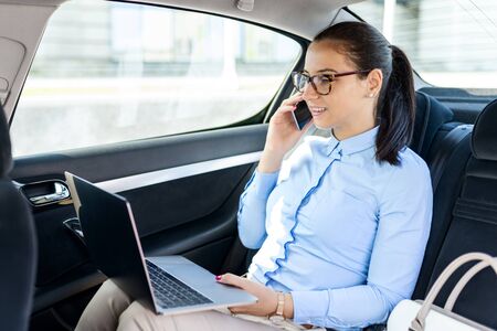 Business woman sitting in the car and talking on the cell. Businesswoman in a car on the phone. Beautiful business woman in the car.Business and lifestyle concept.の写真素材