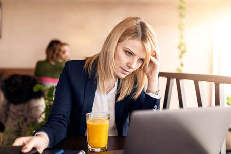 Business woman in cafe with business plan. Beautiful girl is working on laptop. Business and lifestyle concept.の写真素材