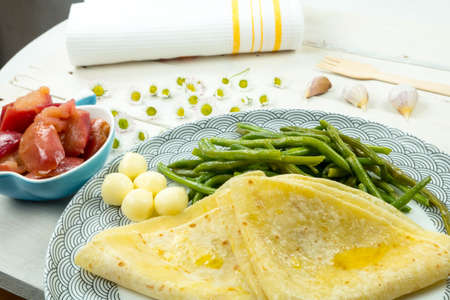 Traditional food from Slovakia. Salty pancake from potato flour dough. Smeared with melted butter. Served with green bean pods, cheese and caramelized sweet apples.の写真素材