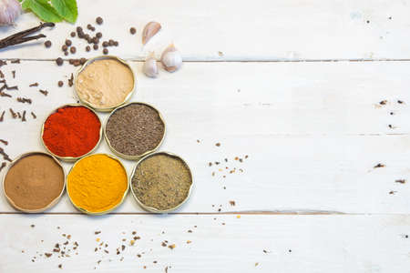 Spices of various kinds and colors on the white old wooden table.