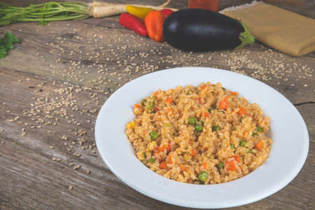 Natural rice with vegetables, risotto on the vintage wooden table decorated with fresh colorful vegetables.の写真素材