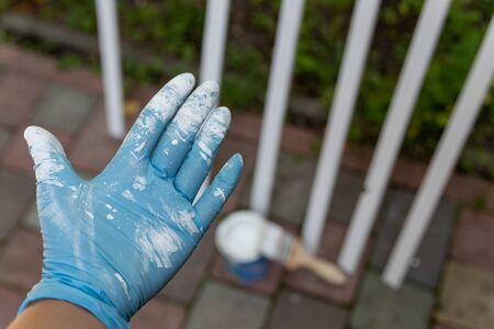 hand in blue rubber mittens covered with white paint on dark backgroundsの写真素材