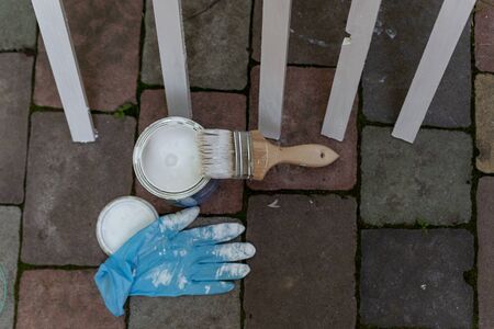paint brush covered with white paint and a jar of paint painted strips on a dark backgroundの写真素材