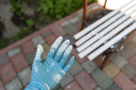 hand in blue rubber mittens covered with white paint on dark backgroundsのeditorial素材