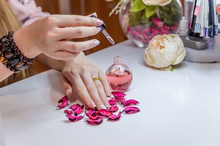 hands care beautiful hands with french manicure cuticle oil white table purple leavesの写真素材