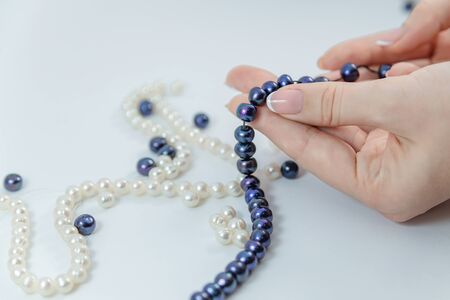 Close-up of hand of needlewoman making necklace of natural pearlsの写真素材