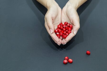 coral beads in woman hands close up on black background