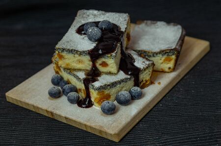 cheesecake with poppy seeds closeup with blueberries on wooden board isolated on black backgroundの写真素材