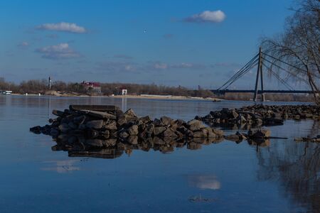rocks on a large lake with blue water and blue sky in early springの写真素材