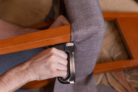 the man restores the chair, covering the soft surface of the chair with a new fabricの写真素材
