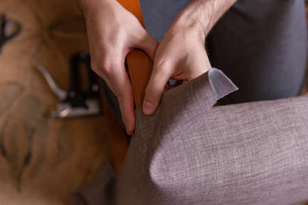the man restores the chair, covering the soft surface of the chair with a new fabric
