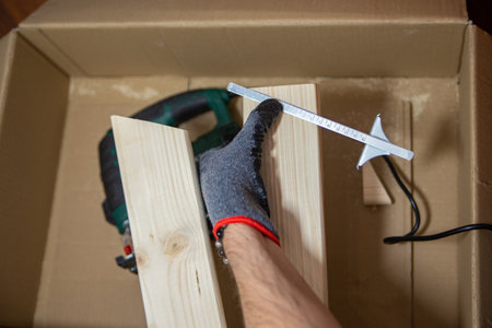 man marks the cut line on a wooden board at home. Do it yourselfの写真素材