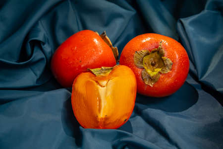 juicy persimmon on a background of blue fabric still lifeの写真素材