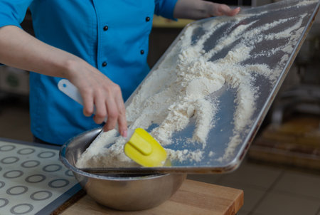 confectioner shifts flour from the pan into a bowl