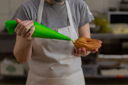 confectioner fills donuts with vanilla creamの写真素材