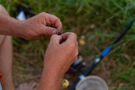 Fisherman stringing bait on a fishing hook on the lake