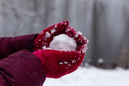 hand in a red glove holds a snowball