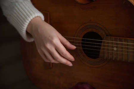female hand playing an old guitar close upの写真素材