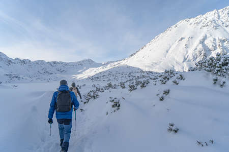 Tatra Mountains, Winter mountain landscape in the Tatras, tourists climb the snowy slopes, views of the snow-capped mountains in frosty sunny weatherの写真素材
