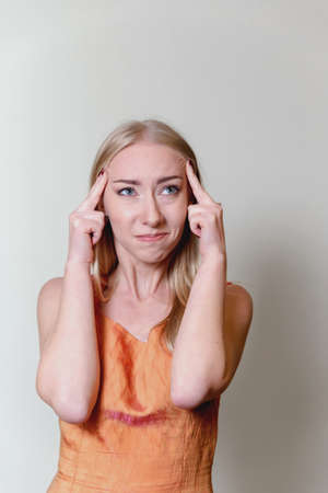 beautiful young blonde woman holding fingers on pulse trying to think looking at camera woman in...