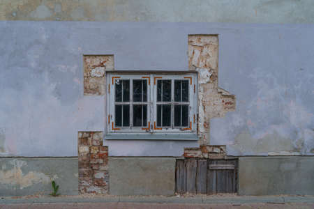 view of plastered wall with old wooden window and cut through plaster to brickwork historic buildingの写真素材