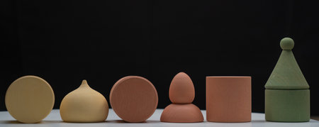 multicolored wooden figurines carved in detail are displayed in a row on a white base on a black...
