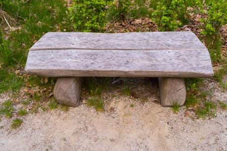 a wooden bench made of pieces of timber on the ground with green grass and stones front photo the...