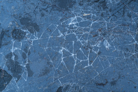 top view of cracked thin ice on the road in early spring in cloudy weather ice texture is like web...