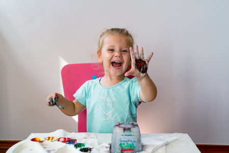 little girl paints an ice castle with colored paints and she is very happy with the process of painting a girl in a blue t-shirt with the inscription "my light" in German, a childの写真素材