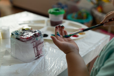 a child paints his hand with colored paints with a brush, close-upの写真素材