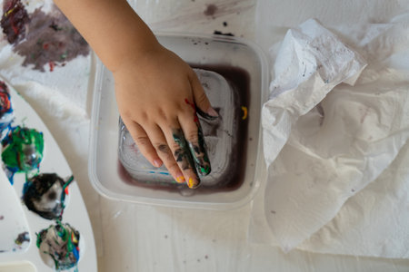 a child's hand paints an ice cube with colored paints, close-up photoの写真素材