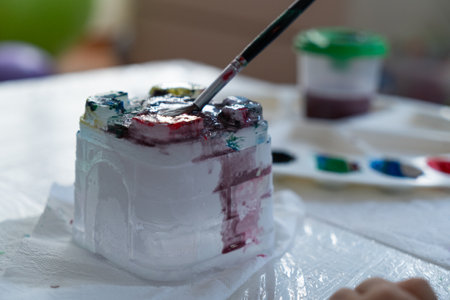 a child paints an ice castle with colored paints with a brush, close-up at homeの写真素材