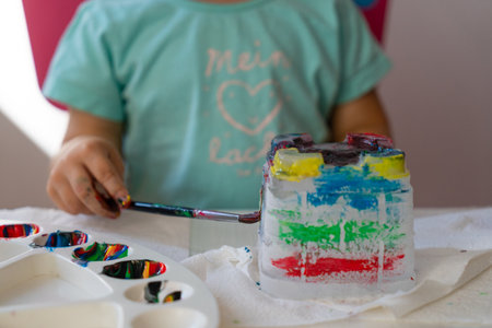 a child paints an ice castle with colored paints with a brush, close-up at homeの写真素材