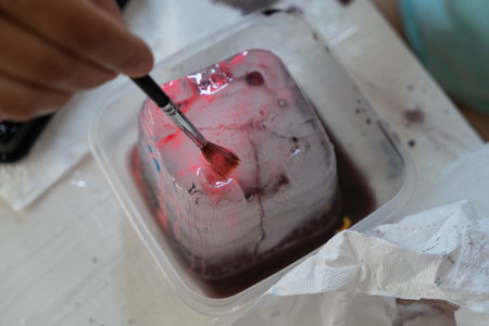 a child paints an ice castle with colored paints with a brush, close-up at homeの写真素材