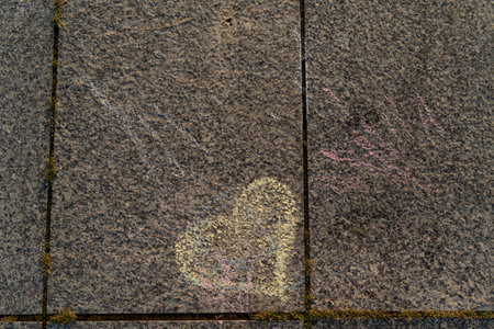 drawn heart with yellow chalk on the roadの写真素材