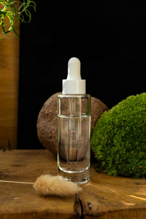 glass transparent bottle with natural cosmetic product and dispenser on moss, stone, tree and black backgroundの写真素材