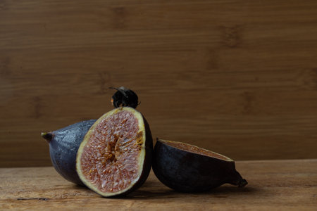 juicy ripe figs cut on a wooden surface on a wooden backgroundの写真素材