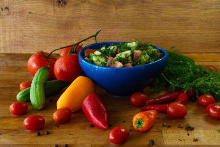 Fresh salad with tomatoes, cucumbers, peppers and dill on wooden backgroundの写真素材