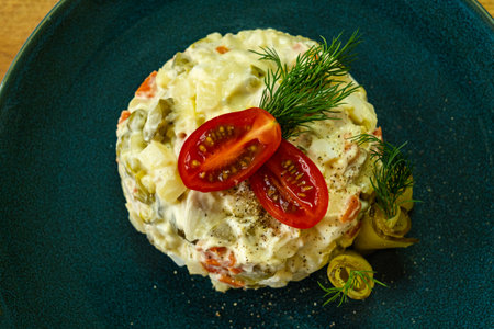 Salad Olivier on a blue plate with fork on wooden backgroundの写真素材