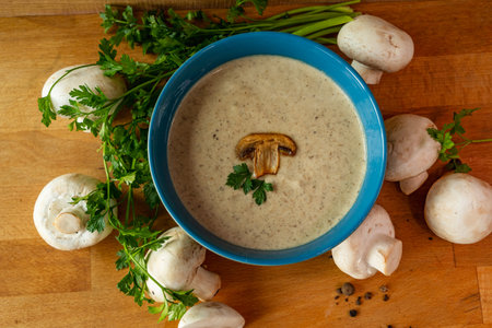 Mushroom cream soup with champignons and parsley on wooden tableの写真素材