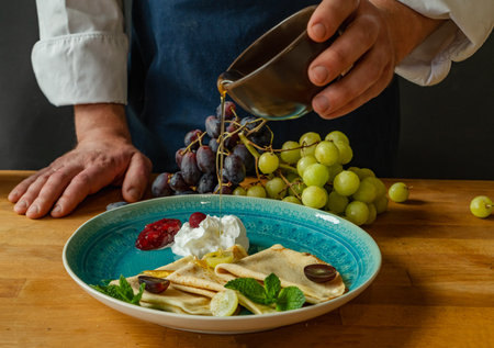 Pancakes with sour cream, grapes and mint on a blue plateの写真素材