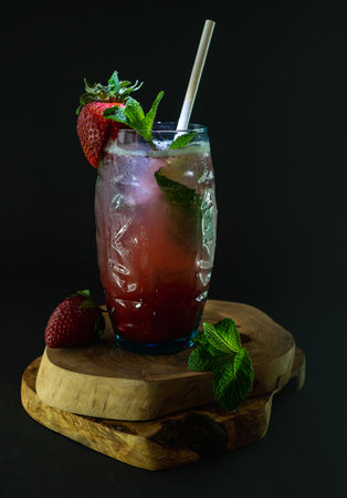 Strawberry mojito cocktail in a glass on a wooden stand on a black backgroundの写真素材