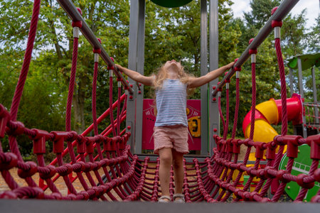 Adorable little girl having fun on a playground in the park.の写真素材