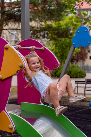 Adorable little girl having fun on a playground in the park.の写真素材